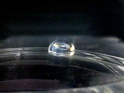 A glass lens prior to plasma treatment displaying its inherent hydrophobic properties